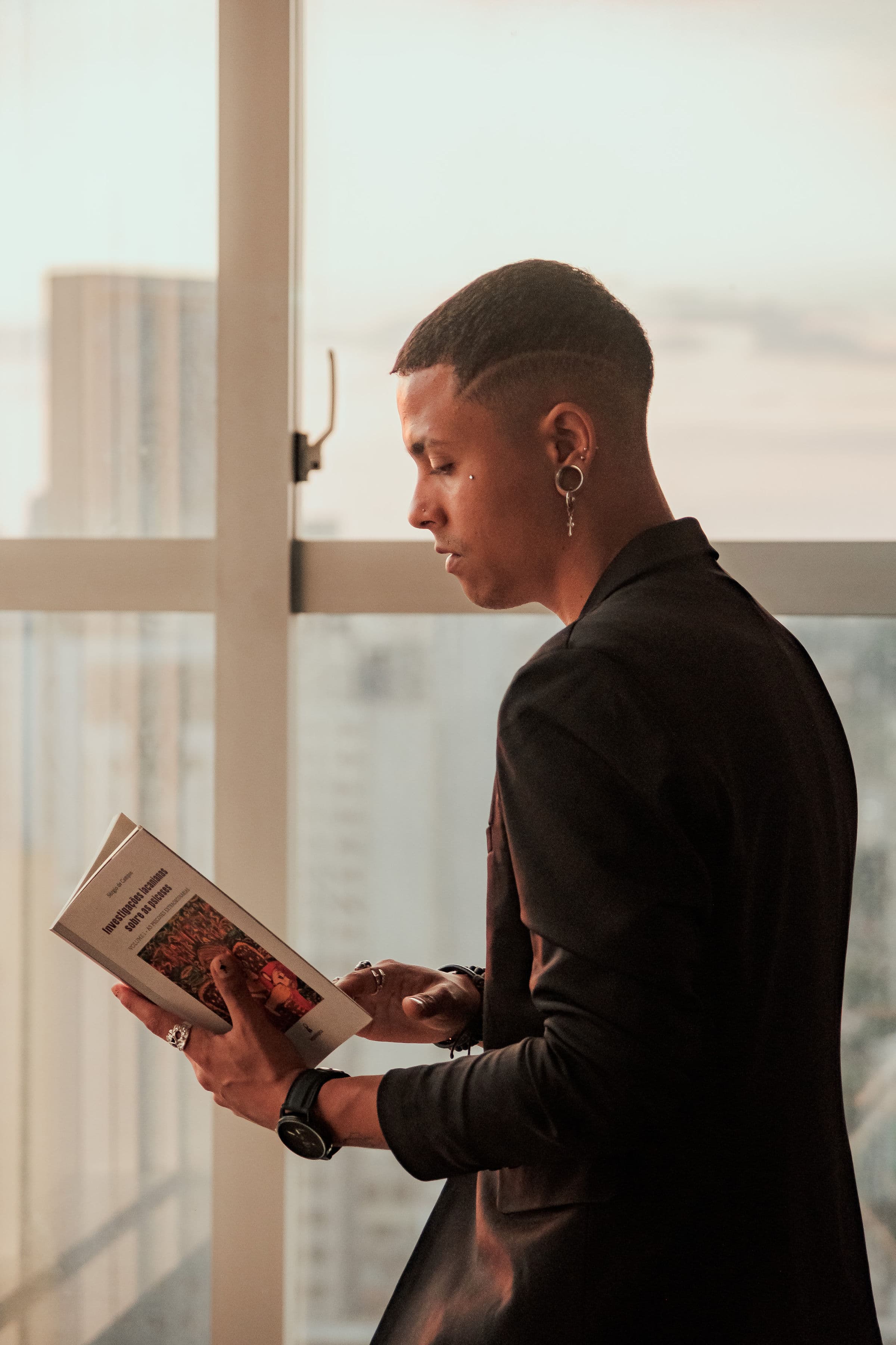 Iury Santos de perfil, lendo junto à janela